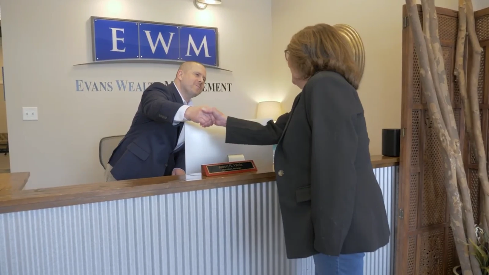 Advisor shaking hands with a client at the Evans Wealth Management reception desk